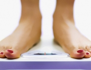 A woman checking her weight on a bathroom scale.