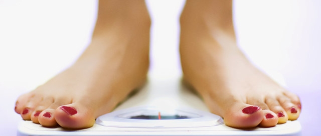 A woman checking her weight on a bathroom scale.